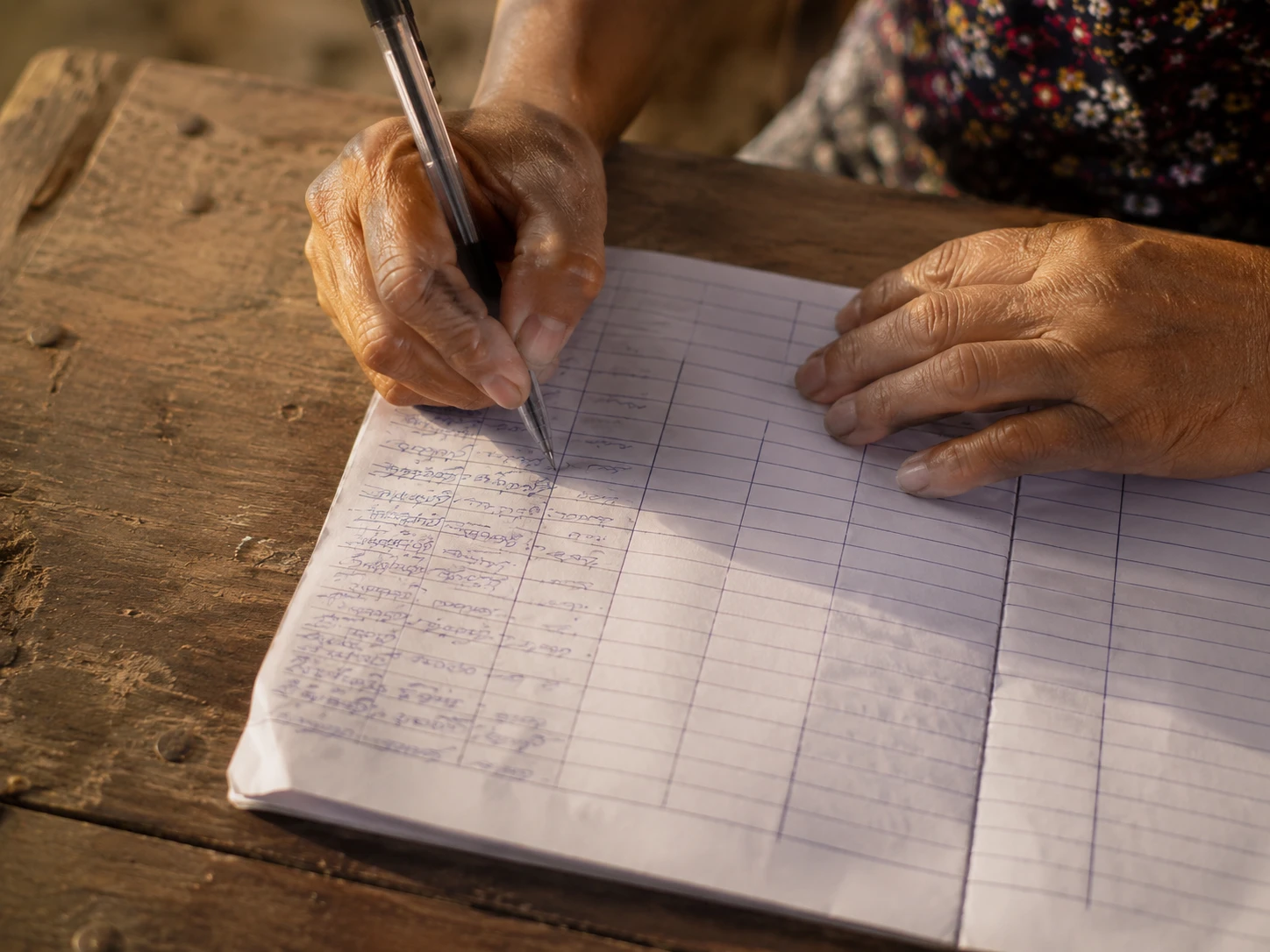 A hand filling in a ruled paper field form with a ballpoint pen